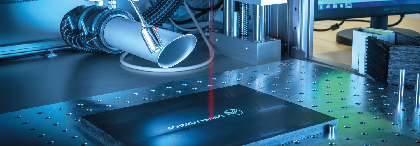 Konfektion & Beschriftung - Platte die, mit Hilfe eines roten Lasers, in Detailaufnahme beschriftet wird.