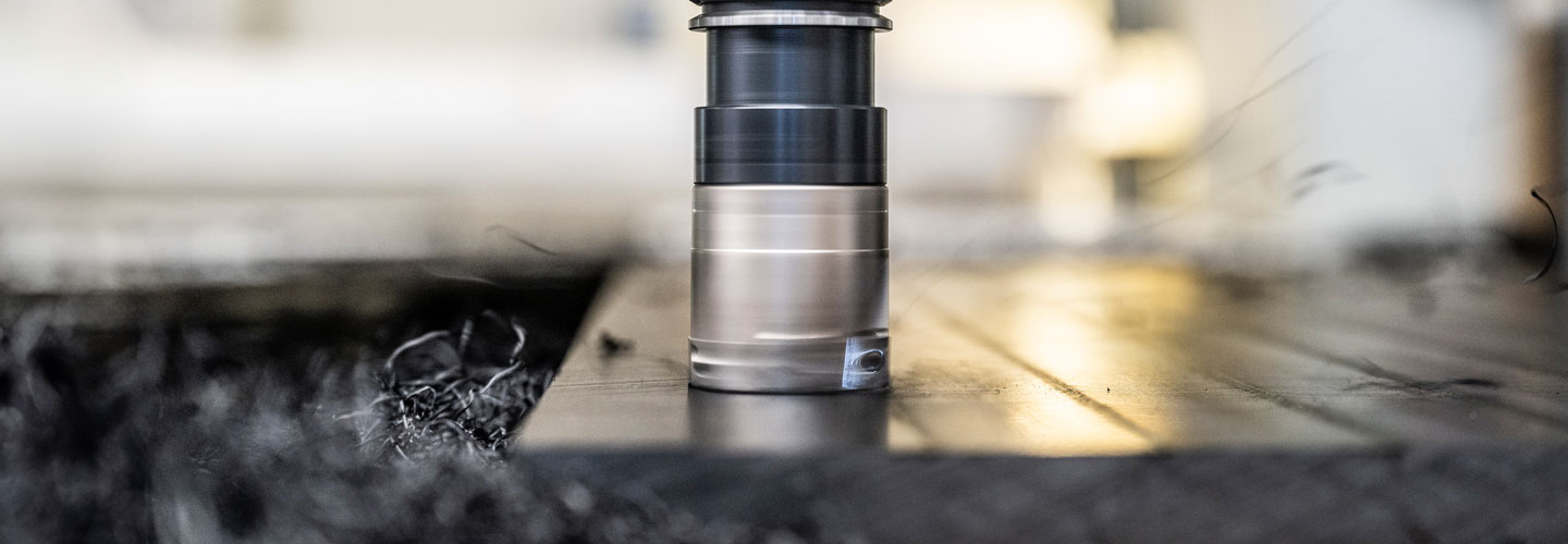 Großaufnahme einer CNC-Fräse: Sie bearbeitet ein Kunststoffstück, während feine Kunststoffspäne entstehen.