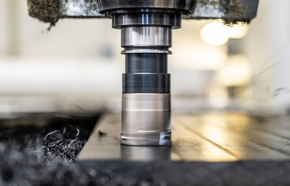 CNC-FRÄSE in Großdarstellung die ein Werkstuck fräst. Neben der Fräse sammeln sich die Metallspäne.